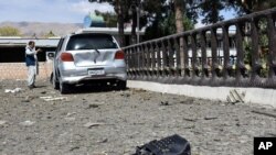 FILE - A man takes pictures at the site of a car bomb blast on an intelligence compound in Aybak, the capital of the Samangan province in northern Afghanistan, July 13, 2020.