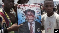Opposition UDPS members hold up blood-splattered poster of leader Etienne Tshisekedi after presidential guard opened fire on crowd outside N'Djili airport in Kinshasa, November 26, 2011.