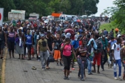 Migrants walk down Highway 200 en route to Huixtla near Tapachula, Chiapas state, Mexico, Oct. 12, 2019. Migrants from Africa, Cuba, Haiti, and other Central American countries set off by foot for the United States.