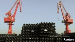 FILE - Cranes are seen above piles of steel pipes to be exported at a port in Lianyungang, Jiangsu province, China, Dec. 1, 2015. 