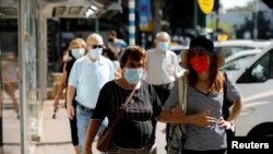 People wearing protective face masks walk down a main street as Israel began easing a second nationwide coronavirus disease (COVID-19) lockdown, in Ramat Gan, Israel, Oct. 18, 2020.