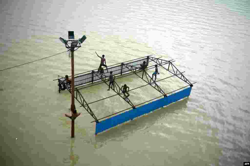 Children of local boatmen play atop a submerged restroom at Daraganj Ghat on the banks of the flooded Ganges River in Allahabad, India.