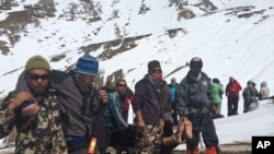 Tentara Nepal, anggota tim SAR membawa korban salju longsor ke daerah yang aman di Thorong La di Nepal, 17 Oktober 2014.