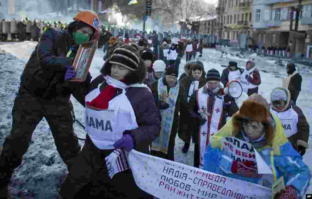 Protesters, with signs reading "Mother" on their chests, and ""The government don't kill our children," walk away from a police cordon in central Kyiv, Jan. 30, 2014.