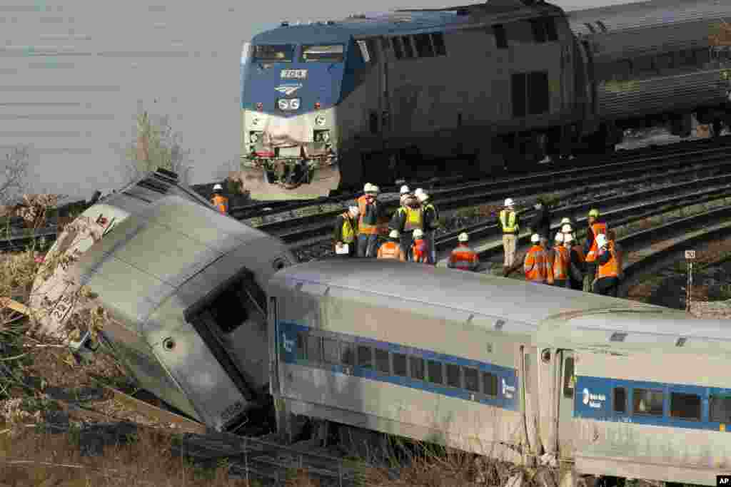 Kereta Amtrak (atas) di jalur yang tidak terganggu, melewati kereta komuter Metro-North yang tergelincir di Bronx, New York, 1 Des., 2013.