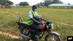 FILE - Yunusa Bawa, a community health worker, rides on a motorbike with a box of AstraZeneca coronavirus vaccines, in Sabon Kuje on the outskirts of Abuja, Nigeria, Dec 6, 2021.