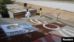 People display portraits of U.S. President Barack Obama on the roof of their houses near Phnom Penh Airport November 14, 2012. Around 182 families living around the airport have been served with eviction notices ahead of Obama's historic visit to the country.