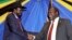 FILE - South Sudan's President Salva Kiir, left, shakes hands with rebel leader and former vice president Riek Machar after signing an agreement to reunify their political party in Arusha, Tanzania, Jan. 21, 2015. 