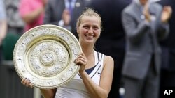 Petra Kvitova dari Republik Ceko memegang tropi kemenangannya setelah mengalahkanMaria Sharapova dalam final putri All England di Wimbledon (2/7/2011).
