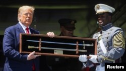 Ketua Kadet Angkatan 2020 West Point, Joshua Phillips, memberikan cindera mata pedang kepada Presiden Donald Trump saat wisuda di Akademi Militer AS, West Point, di New York, 13 Juni 2020. (Foto: Reuters)