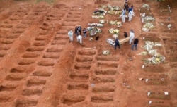 Cemetery workers in protective clothing bury three victims of the new coronavirus at the Vila Formosa cemetery in Sao Paulo, Brazil, July 15, 2020.