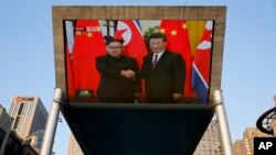 A giant TV screen broadcasts Chinese President Xi Jinping (R) greeting North Korean leader Kim Jong Un, during a welcoming ceremony at the Great Hall of the People in Beijing, China, June 19, 2018. 