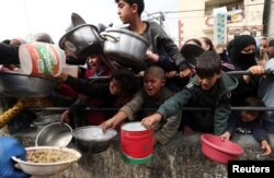 Palestinian children wait to receive food cooked by a charity kitchen amid shortages of food supplies in Rafah in the southern Gaza Strip, Feb. 13, 2024.