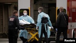 1일 미국 워싱턴주 시애틀 커클랜드의 에버그린헬스 병원에서 보호 장비를 착용한 의료 관계자들이 환자를 구급차로 옮기고 있다. 