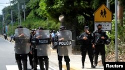 FILE - Nicaraguan police officers block journalists working outside the house of opposition leader Cristiana Chamorro after prosecutors sought her arrest, in Managua, Nicaragua, June 2, 2021.