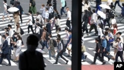 A man sits near a window as people wearing face masks walk along a pedestrian crossing at Shibuya district Sept. 30, 2021, in Tokyo. 