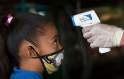 A health worker takes a child's temperature to help curb the spread of the new coronavirus, at the Central de Abasto market in Mexico City, Thursday, June 18, 2020. (AP Photo/Marco Ugarte)
