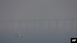 FILE - A boat navigates the Negro River amid smoke from wildfires in Manaus, Amazonas state, Brazil, Aug. 27, 2024.