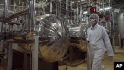 FILE - Wearing protective clothes, an Iranian security person walks at a part of the Uranium Conversion Facility just outside the city of Isfahan, Iran. Iran has removed the sensitive core of its Arak nuclear reactor and U.N. inspectors will visit the site on Thursday to verify.