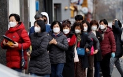 People wearing masks stand in a line to buy face masks in front of a drug store amid the rise in confirmed cases of the novel coronavirus disease of COVID-19 in Daegu, South Korea, March 3, 2020.