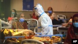 A health worker talks to a woman in a quarantine center for COOVID-19 patients, in New Delhi, India, April 19, 2021. 