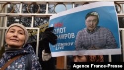 A woman holds a banner with a portrait of journalist Bolot Temirov as people take part in a rally calling for a stop to the persecution of journalists and for the release of Temirov, who was detained the night before, in Bishkek, Kyrgyzstan, Jan. 23, 2022