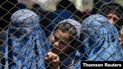 FILE PHOTO: Afghan women wait to receive free wheat donated by the Afghan government during a quarantine, amid concerns about the coronavirus disease (COVID-19) in Kabul