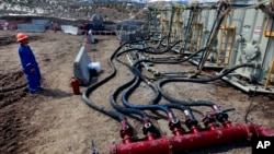 A worker helps monitor water pumping pressure and temperature, at a hydraulic fracturing and extraction site, outside Rifle, in western Colorado, March 29, 2013. 