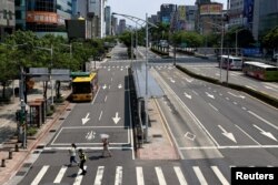 Seorang petugas polisi meminta orang-orang untuk mencari perlindungan selama latihan serangan udara tahunan yang bernama Wan An, 25 Juli 2022. (Foto: REUTERS/Ann Wang)