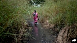 Mwanamke akipita kwenye njia iliyofurika maji katika kijiji cha Dijeri, katika vitongoji vya Juba, Sudan Kusini, Oktoba 1, 2021. Picha ya AP