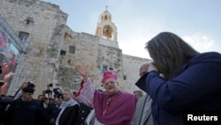 Kepala kelompok agama Kristen di Yerusalem, Fouad Twal melambaikan tangannya setibanya di Bethlehem, Tepi Barat untuk menghadiri perayaan Natal (24/12).