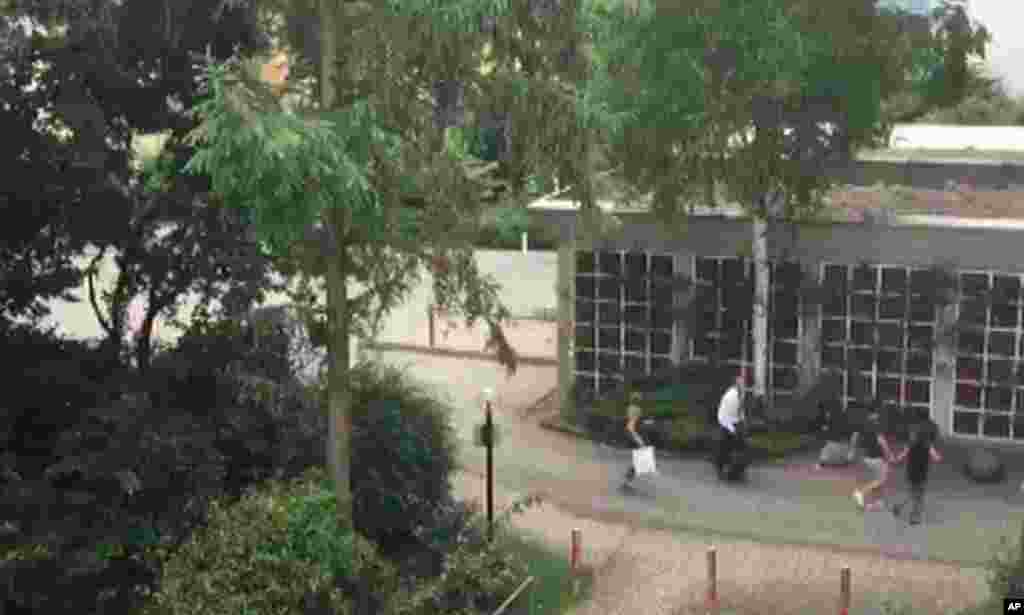 In this frame grab taken from video, people run from the Olympia Einkaufszentrum shopping center in Munich, Germany, after a shooting, July 22, 2016.