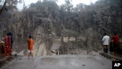 Villagers look at the broken bridge destroyed by the lava flow by the eruption of Mount Semeru in Lumajang district, East Java province, Indonesia, Dec. 5, 2021.