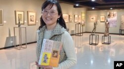 In this photo taken on March 23, 2021, Taiwanese author Iris Chiang holds her book "Play with Art" at an event featuring Taiwanese artist YUYU Yang's work in Taipei, Taiwan. (AP Photo/Chiang Ying-ying)