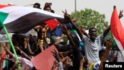 FILE - People shout slogans as tens of thousands of people march on the streets demanding the ruling military hand over to civilians, in Khartoum, Sudan, June 30, 2019.