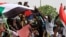 FILE - People shout slogans as tens of thousands of people march on the streets demanding the ruling military hand over to civilians, in Khartoum, Sudan, June 30, 2019.
