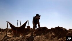A Kurdish Peshmerga fighter uses binoculars to check on Islamic State group's positions on the outskirts of Makhmour, 300 kilometers (186 miles) north of Baghdad, Iraq, Sept. 6, 2014. 