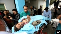 Warga Afghanistan membantu seorang pria yang terluka di rumah sakit setelah terjadinya serangan bunuh diri (21/11). Kabul, Afghanistan. (foto: AP Photo/Rahmat Gul)