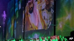 In this file photo taken Saturday Sept. 23, 2017, Saudi men perform under a giant screen showing an image of Saudi Crown Prince Mohammed Bin Salman during National Day ceremonies, at the King Fahd Stadium in Riyadh, Saudi Arabia. (Saudi Press Agency via AP)