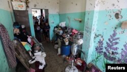 23일 이스라엘 군의 공습을 피해를 팔레스타인 난민들을 수용하는 건물 내의 방 앞에 어린이들이 서있다.