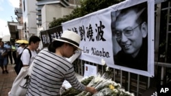 Seorang wanita berduka atas kepergian penerima Hadiah Nobel Perdamaian asal China, Liu Xiaobo, di luar kantor penghubung China di Hong Kong, Jum’at, 14 Juli 2017 (foto: AP Photo/Kin Cheung)