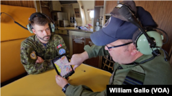 Major Doug Publicover, right, and Captain Maxime Cliche examine a tablet on board a Canadian CP-140 over the East China Sea, Oct. 14, 2024.