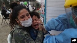 Sofia Pinto holds her son Antonio who cries out as he receives an influenza vaccine during a vaccination campaign in the Villa El Salvador neighborhood of Lima, Peru, June 26, 2020.