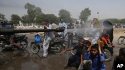 FILE - A Pakistani volunteer sprays water on people to keep them cool as temperatures reached 43 Celsius (109.4 Fahrenheit) in Karachi, Pakistan, May 21, 2018. 