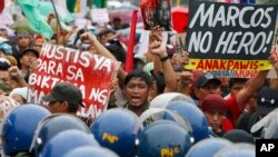 Para pemrotes memegang plakat saat melakukan aksi demo di dekat gerbang Taman Makam Pahlawan di kota pinggiran Taguig, sebelah timur Manila, Filipina, untuk memprotes demonstrasi massal dan perayaan HUT ke-100 mendiang diktator Filipina Ferdinand Marcos, Senin, 11 September 2017. 