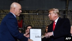 President Donald Trump hands U.S. General John W. Raymond a document after signing the ‘National Defense Authorization Act for FY2020’ at Joint Base Andrews, Maryland, on Dec. 20, 2019.