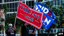 ក្រុម​អ្នក​គាំទ្រ​​លោក ដូណាល់ ត្រាំ បេក្ខជន​ប្រធានាធិបតី​ខាង​គណបក្ស​សាធារណរដ្ឋ (ឆ្វេង) និង​លោក Joe Biden បេក្ខជន​ប្រធានាធិបតី​ខាង​គណបក្ស​ប្រជាធិបតេយ្យ កាន់​ទង់​គាំទ្រ​អ្នក​ទាំងពីរ​រៀងខ្លួន នៅ​រដ្ឋ Florida ថ្ងៃទី៥ ខែតុលា ឆ្នាំ២០២០។