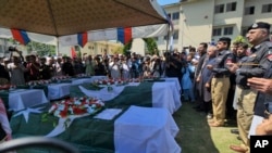 Des responsables et d'autres personnes assistent à la prière funéraire des policiers tués dans les explosions de lundi à Kaboul, une ville du district pakistanais de Swat, le mardi 25 avril 2023.