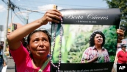 FILE - A woman holds up a poster with a photo of slain environmental leader Berta Caceres, during a protest march in Tegucigalpa, Honduras.