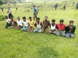 FILE - Ten Rohingya men with their hands bound kneel as members of the Myanmar security forces stand guard in Inn Din village of Rakhine State, Myanmar, Sept. 2, 2017.
